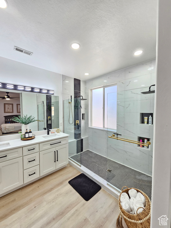 Full bath with ceiling fan, vanity, a shower stall, wood finished floors, and visible vents
