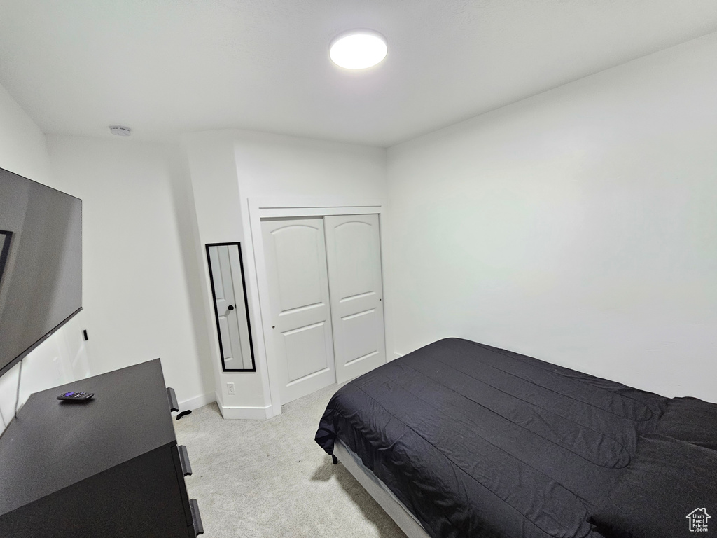 Bedroom with baseboards, light colored carpet, and a closet