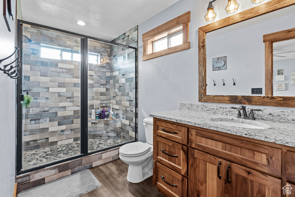 Full bathroom with a stall shower, vanity, toilet, and wood finished floors