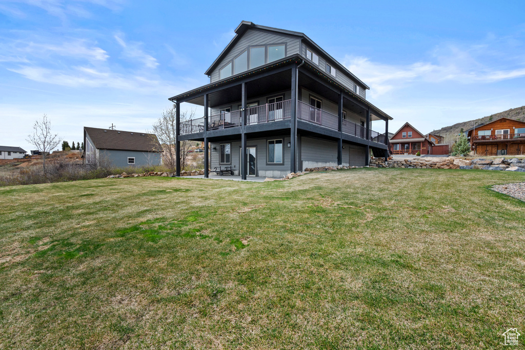 Back of house featuring a patio area, a lawn, and a balcony