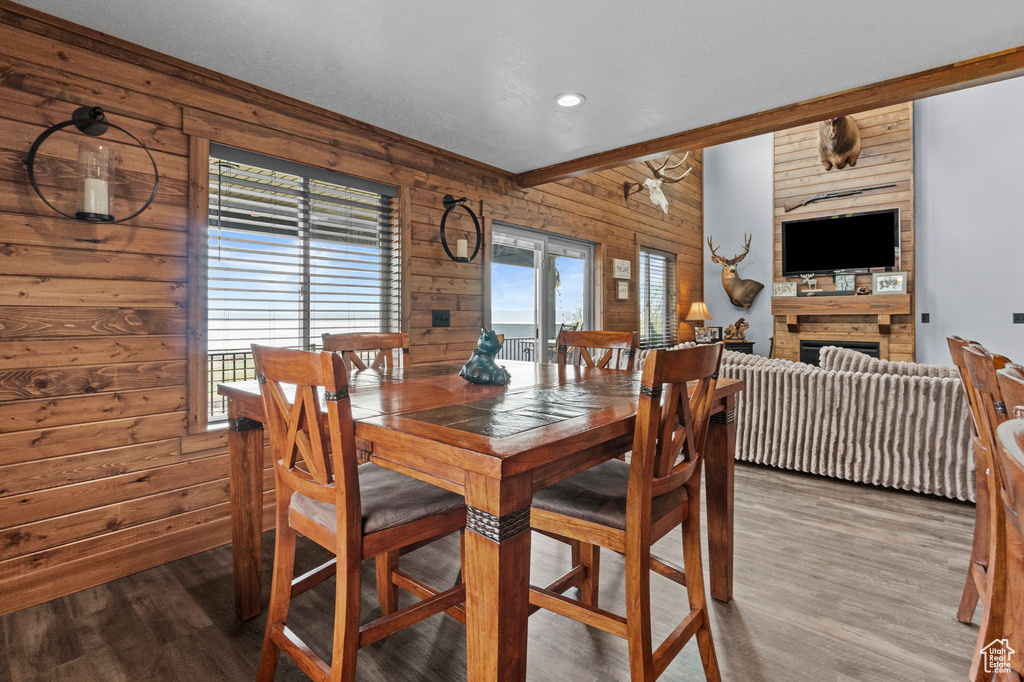 Dining space with wooden walls, a fireplace, and wood finished floors