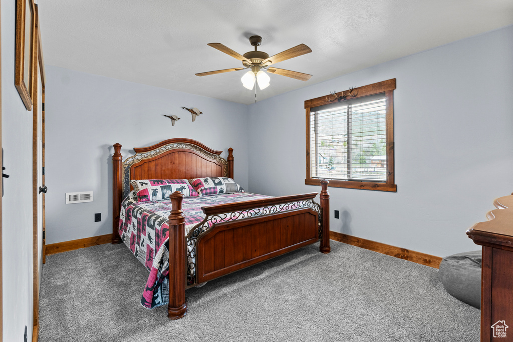 Carpeted bedroom featuring baseboards, visible vents, and a ceiling fan