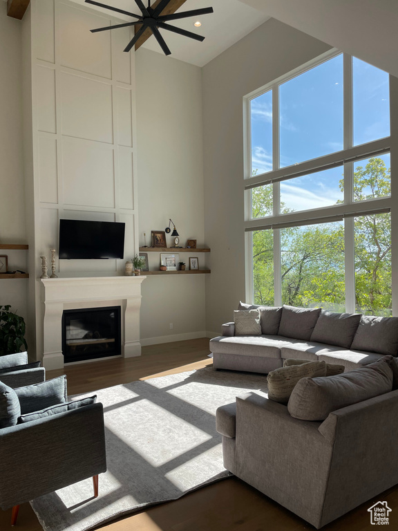 Living area featuring a ceiling fan, a large fireplace, wood finished floors, baseboards, and recessed lighting