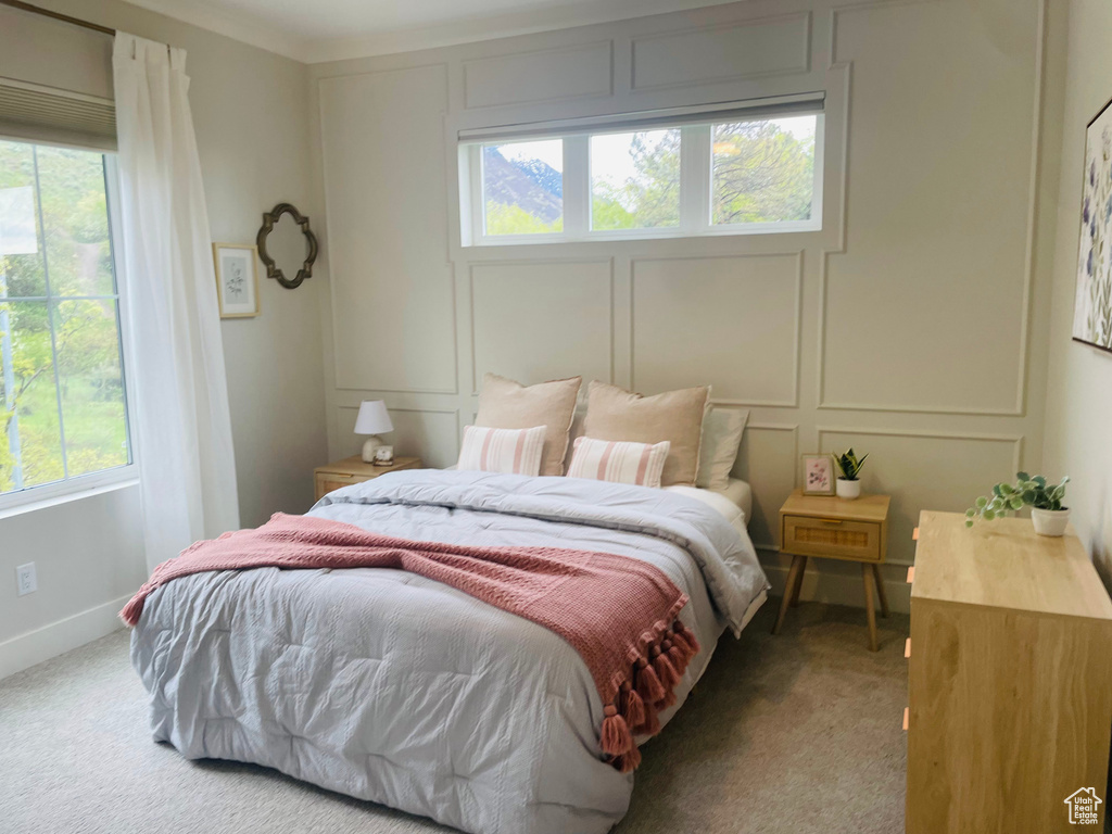 Bedroom with carpet floors, multiple windows, and a decorative wall