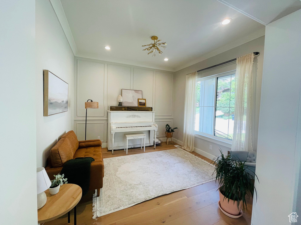 Living area featuring a decorative wall, crown molding, wood finished floors, and recessed lighting