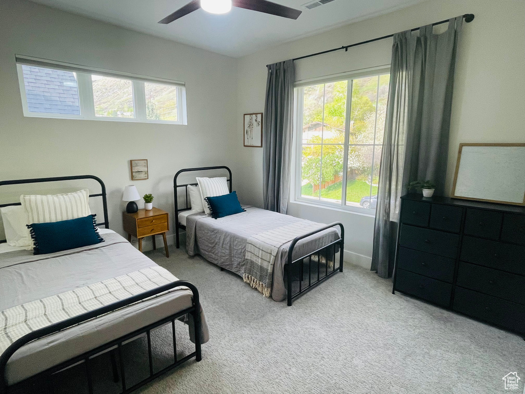 Carpeted bedroom with visible vents, ceiling fan, and multiple windows