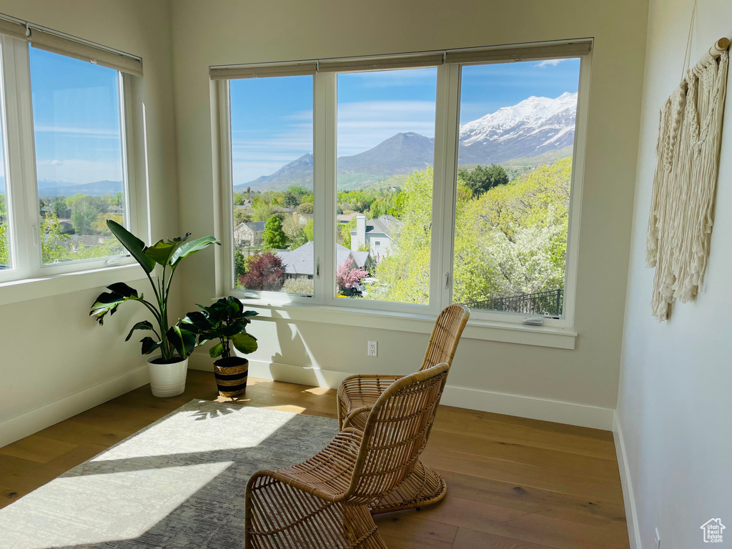 Sunroom with baseboards, a mountain view, and wood finished floors