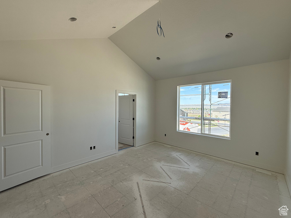 Unfurnished bedroom featuring high vaulted ceiling and baseboards