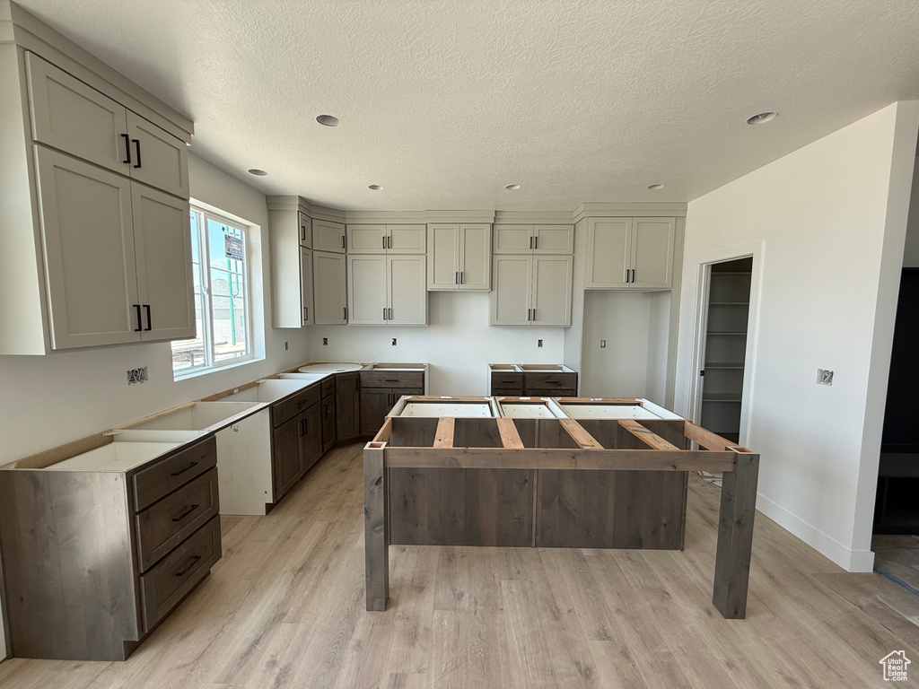 Kitchen with light wood-style flooring, a center island, a textured ceiling, gray cabinetry, and recessed lighting