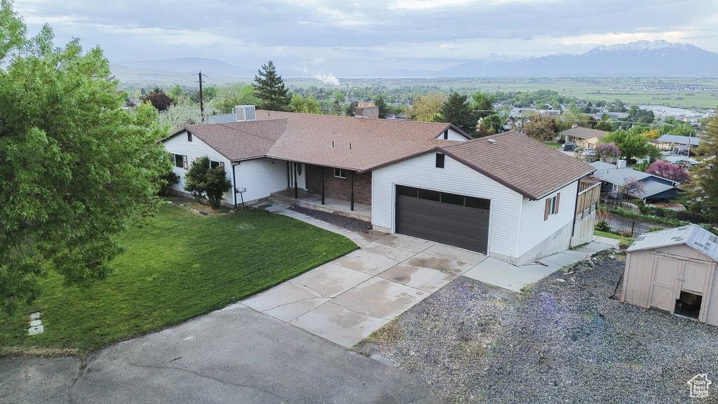 Ranch-style house with a mountain view, a front lawn, a garage, and covered porch