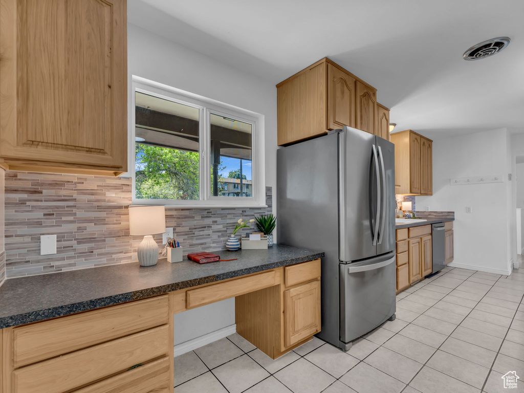 Kitchen featuring built in desk, light tile patterned floors, stainless steel appliances, visible vents, and backsplash