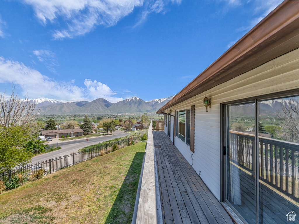 Wooden terrace featuring fence, a mountain view, and a lawn