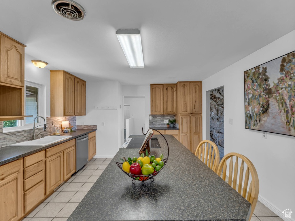 Kitchen featuring a sink, dark countertops, dishwasher, decorative backsplash, and light tile patterned flooring