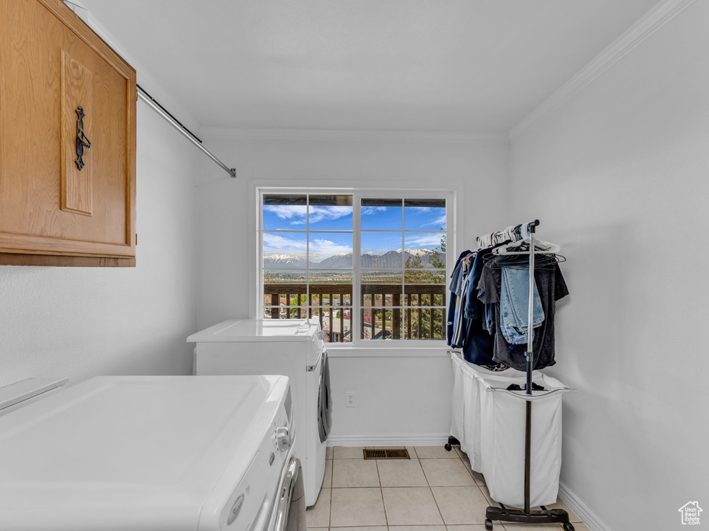 Laundry room with light tile patterned flooring, visible vents, crown molding, washing machine and clothes dryer, and cabinet space