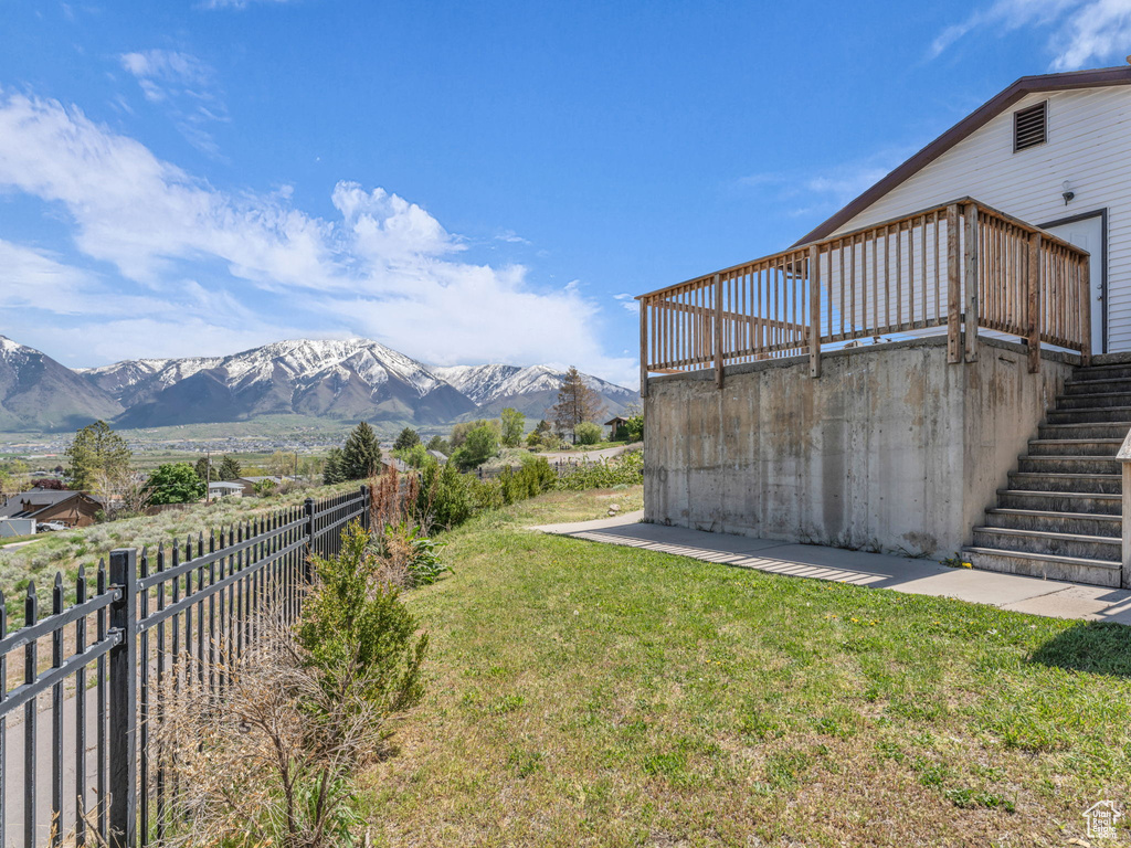View of yard featuring stairs, a deck with mountain view, and a fenced backyard
