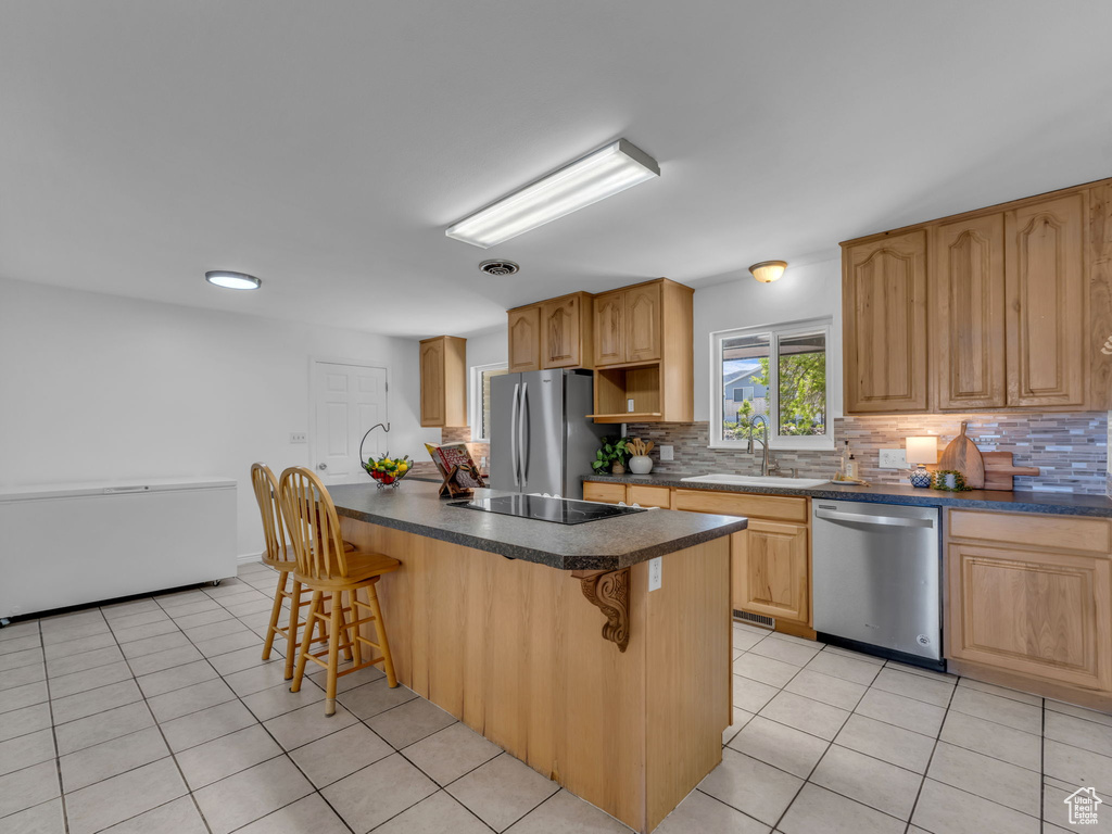 Kitchen with a sink, stainless steel appliances, a kitchen bar, and decorative backsplash