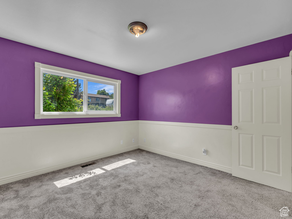 Carpeted empty room with baseboards and visible vents