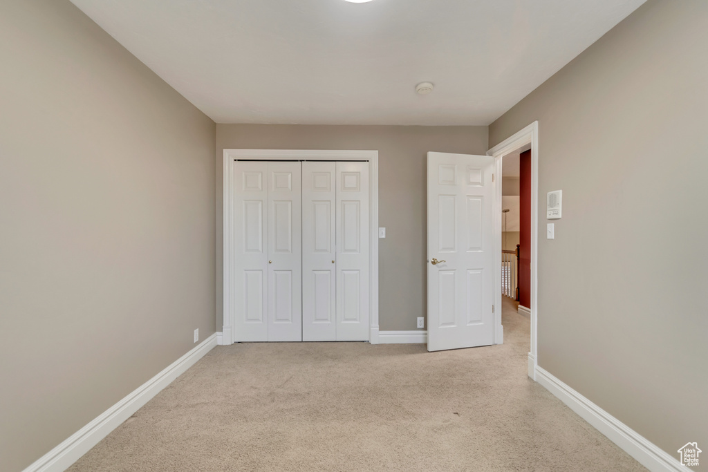 Unfurnished bedroom with light colored carpet, baseboards, and a closet