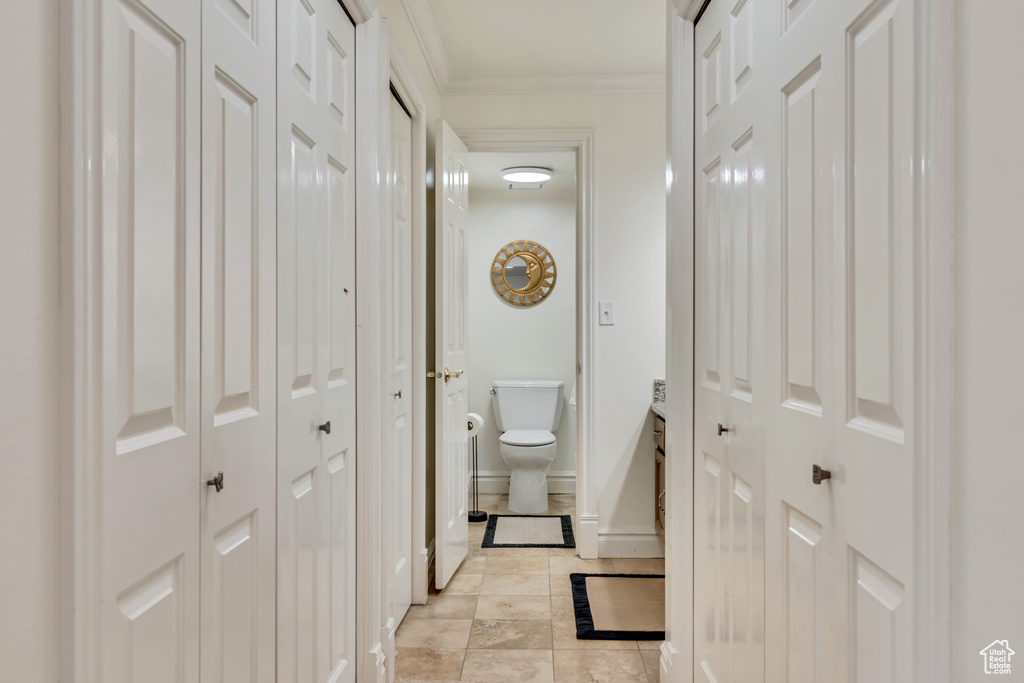 Hallway with light tile patterned floors, baseboards, and ornamental molding