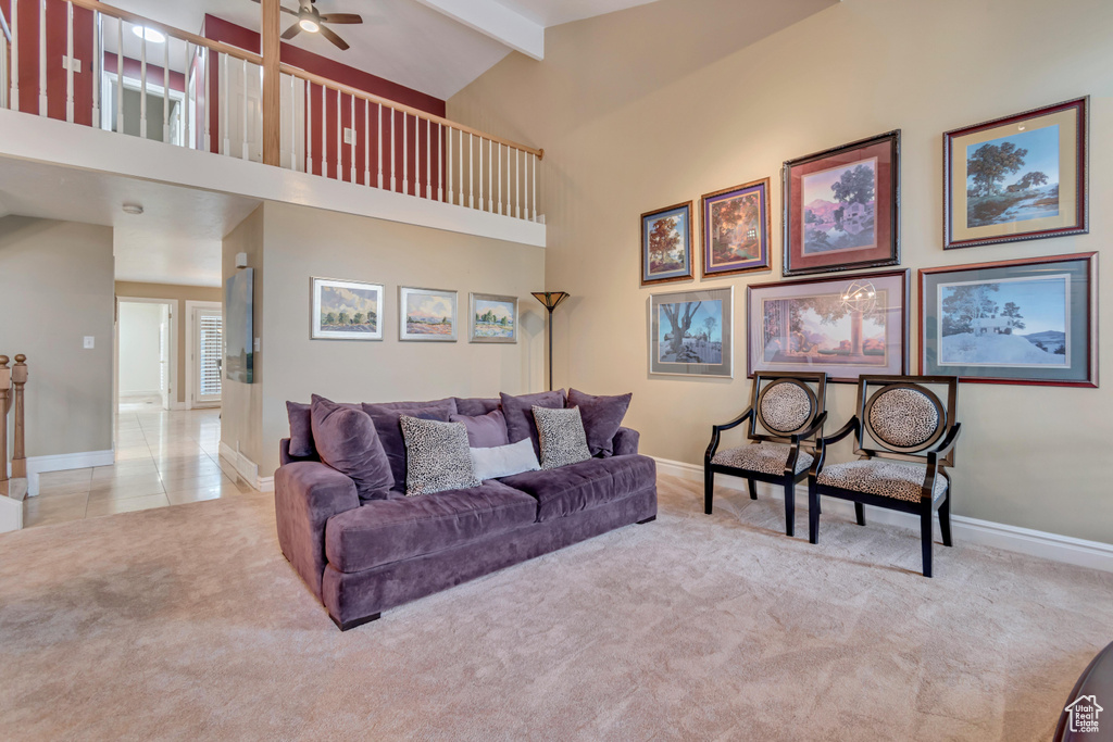 Living room featuring beamed ceiling, baseboards, a ceiling fan, and carpet