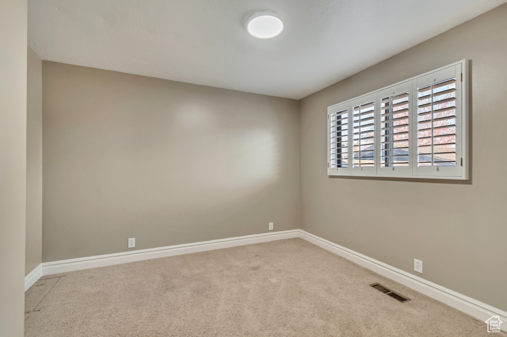 Carpeted spare room featuring visible vents and baseboards