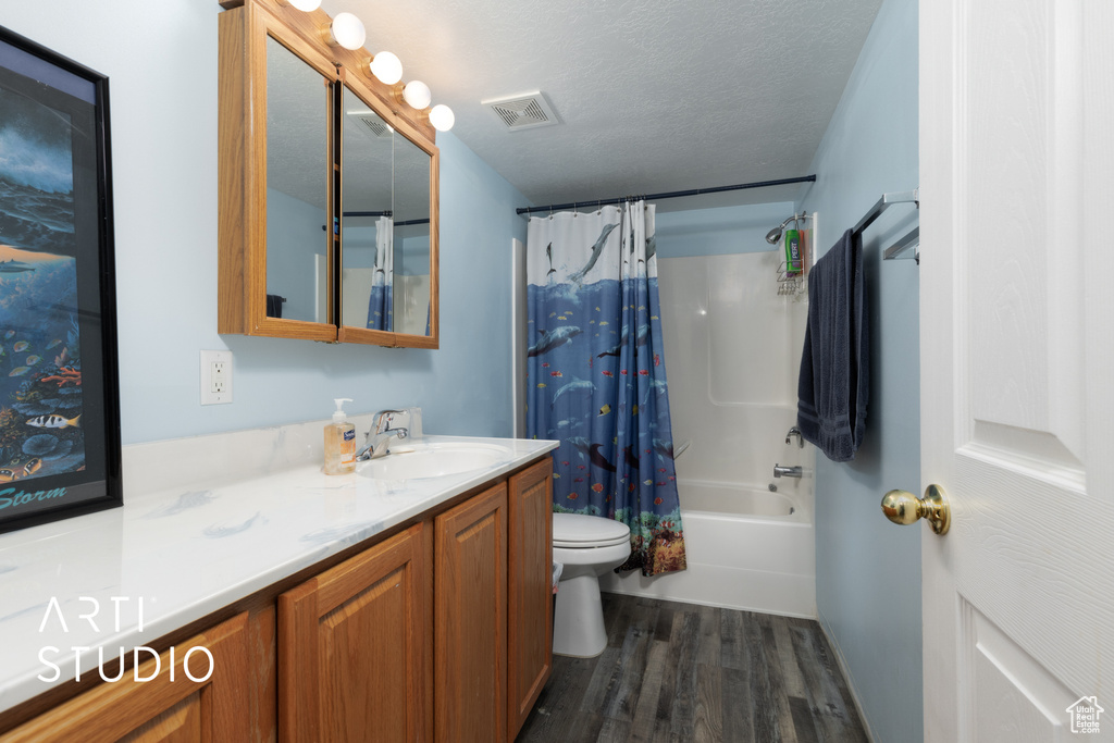 Bathroom with shower / bath combo with shower curtain, toilet, visible vents, vanity, and wood finished floors