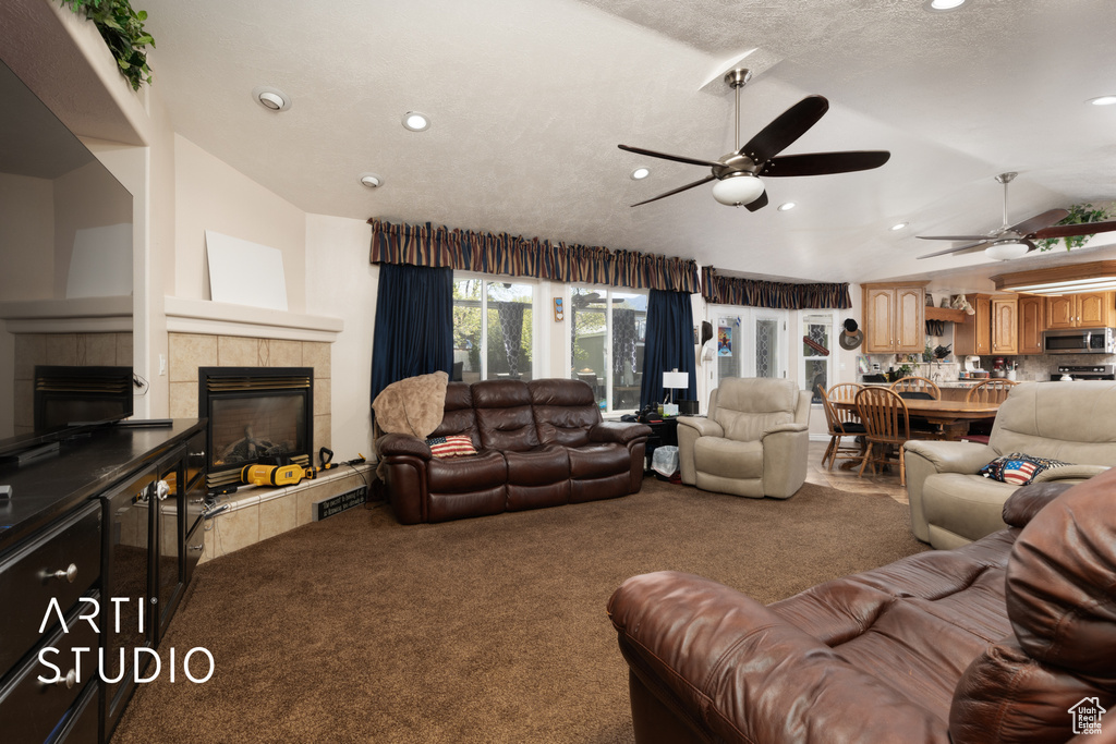 Living room featuring a ceiling fan, lofted ceiling, recessed lighting, carpet flooring, and a tile fireplace