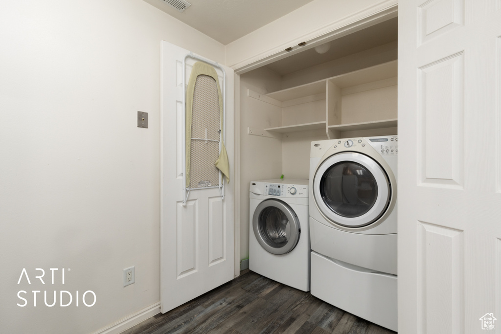 Washroom featuring separate washer and dryer, laundry area, dark wood-style flooring, and baseboards