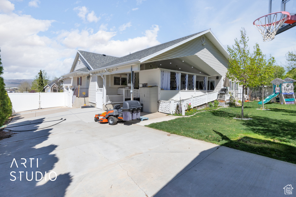 View of front facade with a gate, fence, a shingled roof, a front yard, and a playground