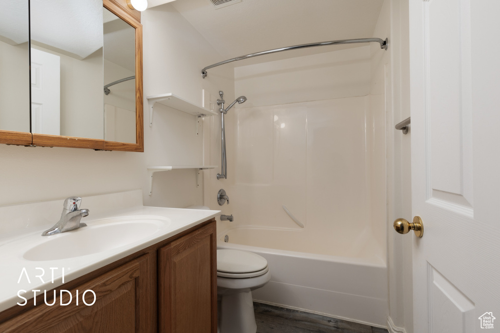 Bathroom featuring toilet, visible vents, vanity, bathtub / shower combination, and wood finished floors