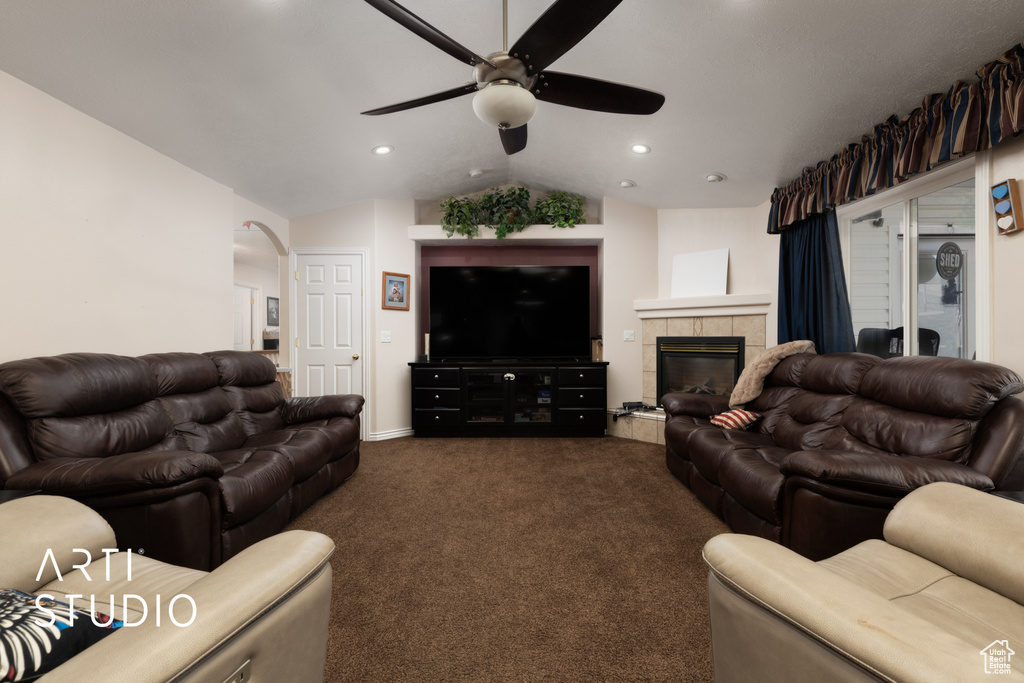 Living area featuring a ceiling fan, lofted ceiling, recessed lighting, dark colored carpet, and a tile fireplace