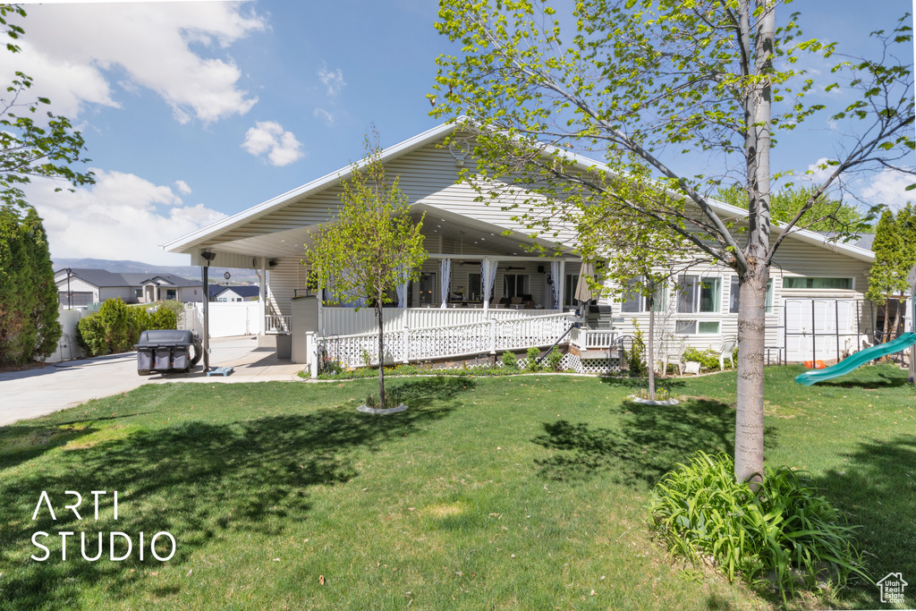 View of front of house featuring a porch, fence, a playground, and a front lawn