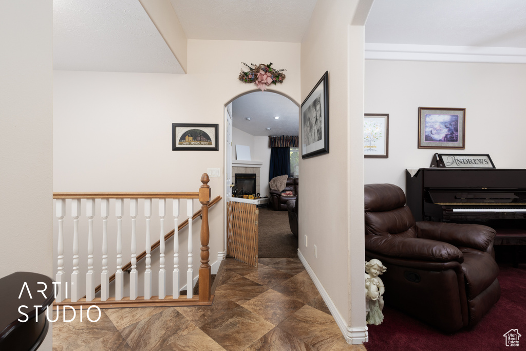 Corridor with an upstairs landing, baseboards, stone finish flooring, and arched walkways