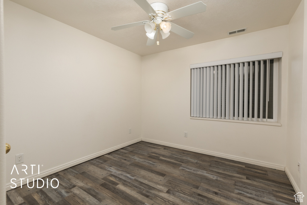 Empty room featuring ceiling fan, baseboards, visible vents, and dark wood finished floors