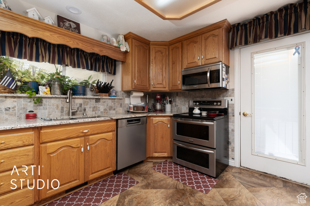 Kitchen with a sink, stainless steel appliances, decorative backsplash, and brown cabinets