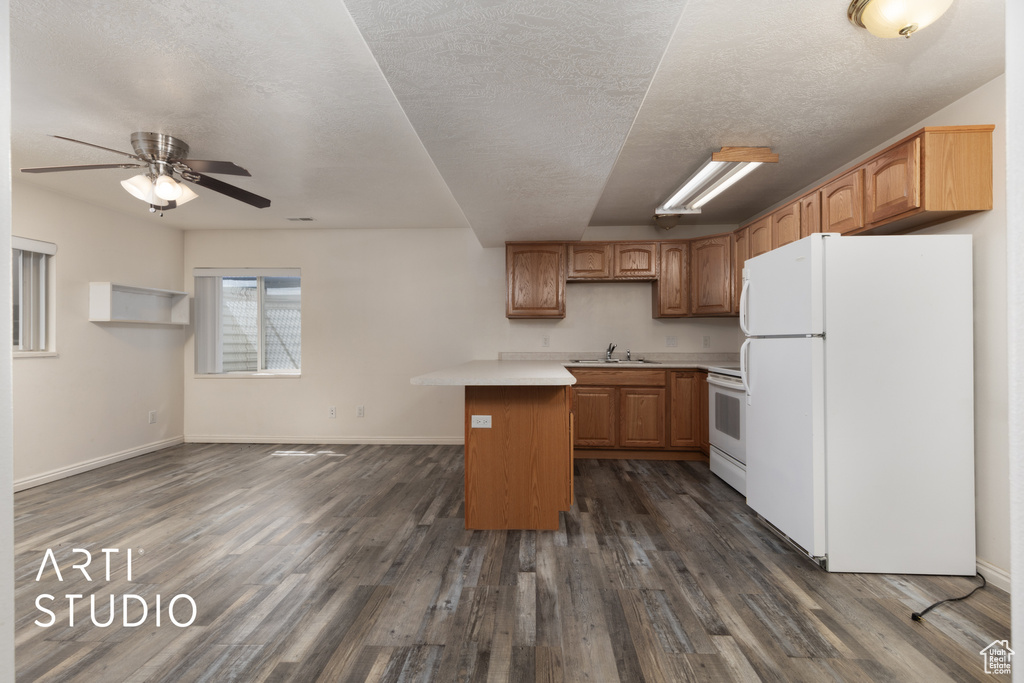 Kitchen with baseboards, white appliances, dark wood finished floors, a sink, and light countertops