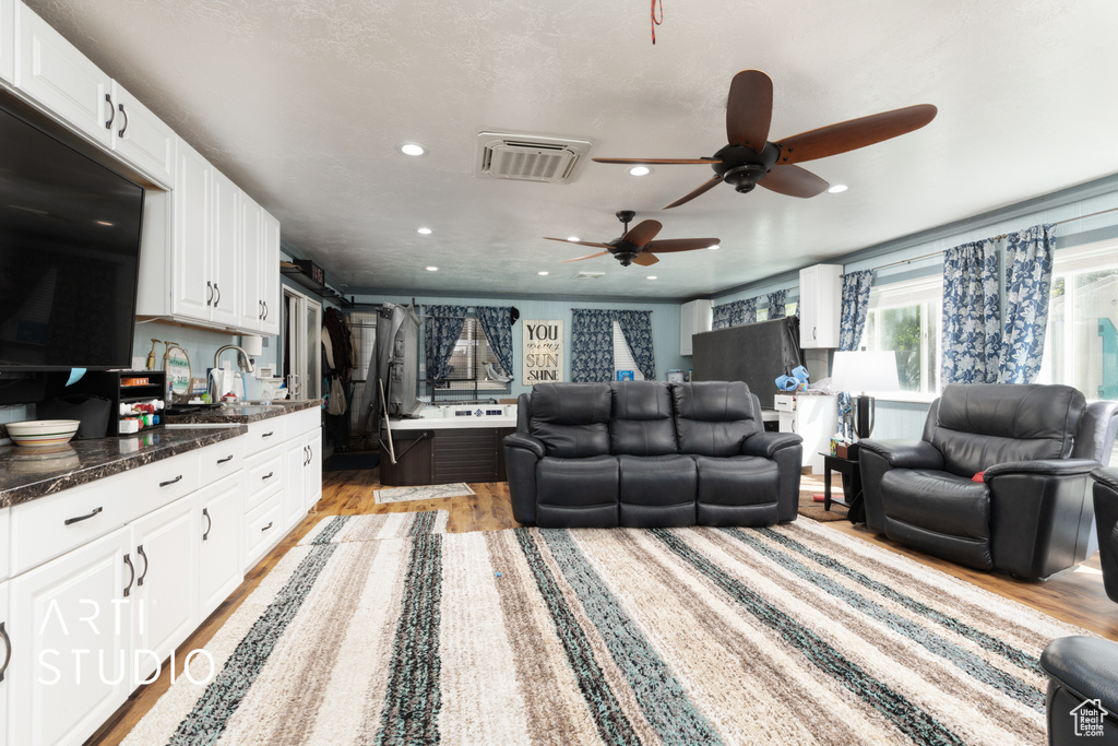 Living room with light wood finished floors, ceiling fan, and recessed lighting