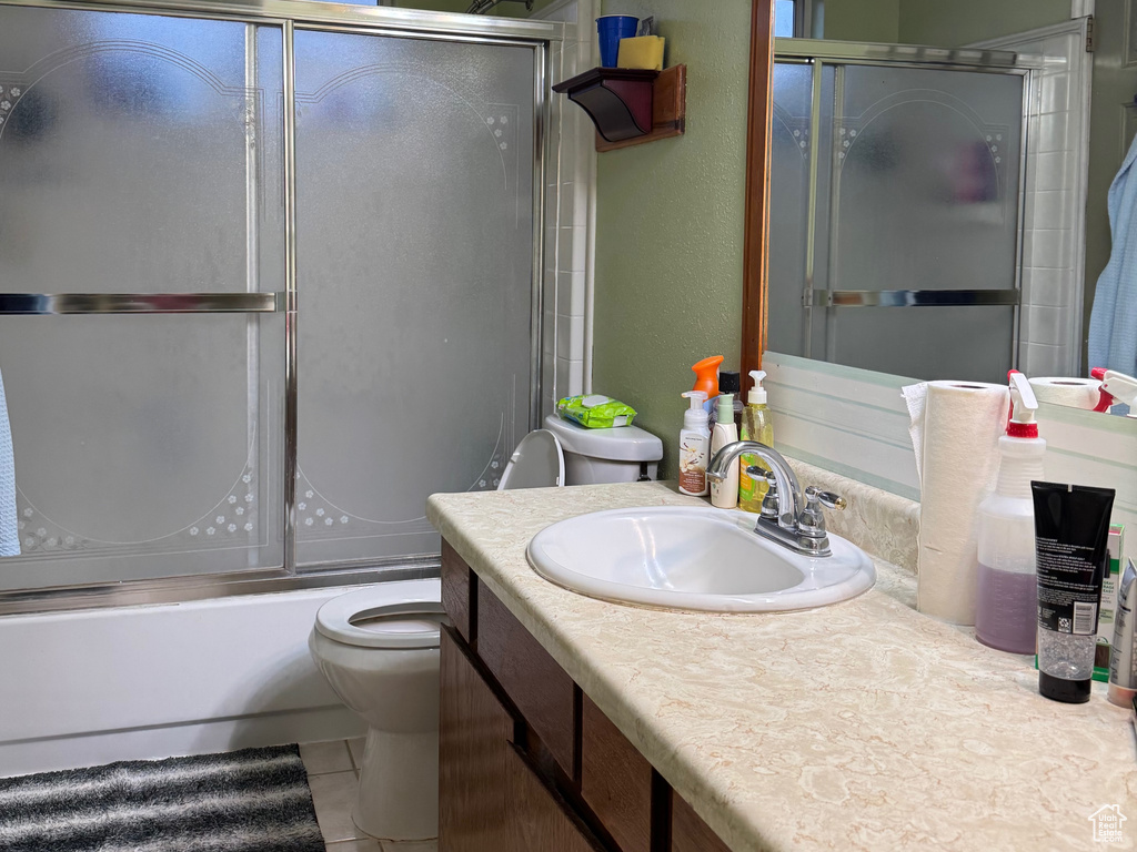 Bathroom featuring vanity, toilet, combined bath / shower with glass door, and tile patterned flooring