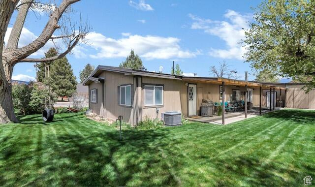 Back of house featuring a yard, cooling unit, and a patio