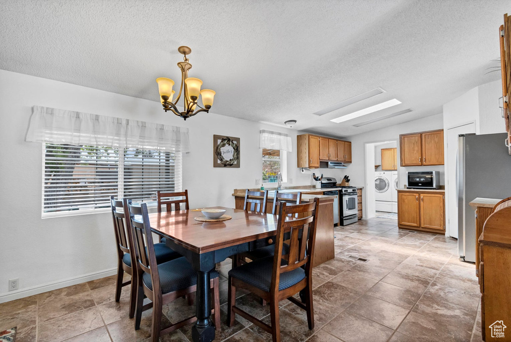 Dining area with a textured ceiling, a notable chandelier, baseboards, and visible vents