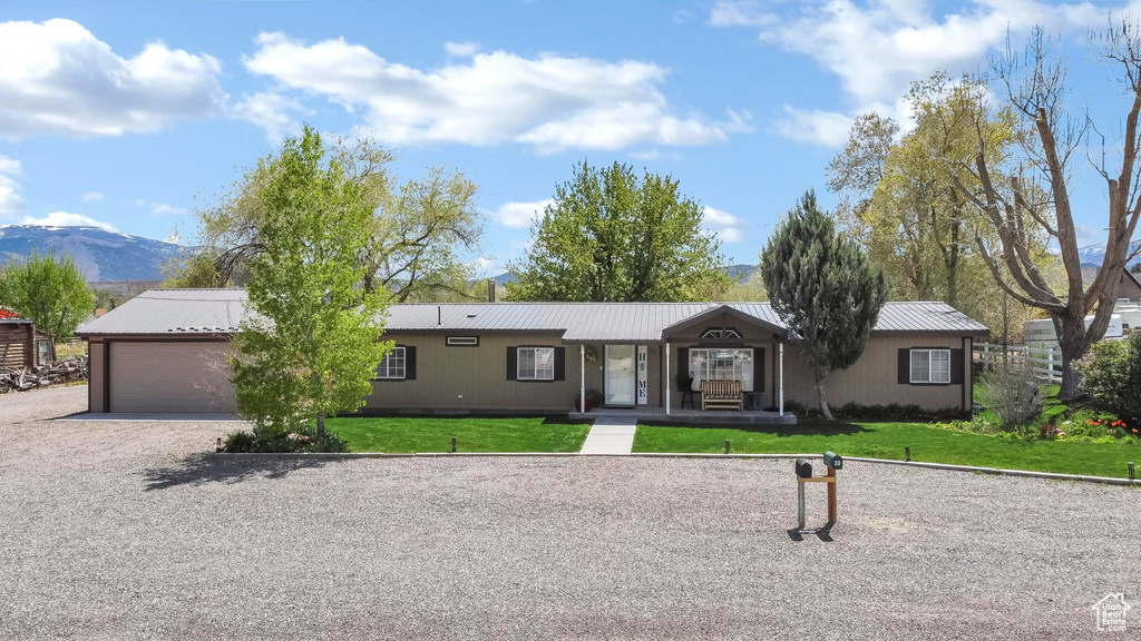 Ranch-style home with a front lawn, a garage, and metal roof