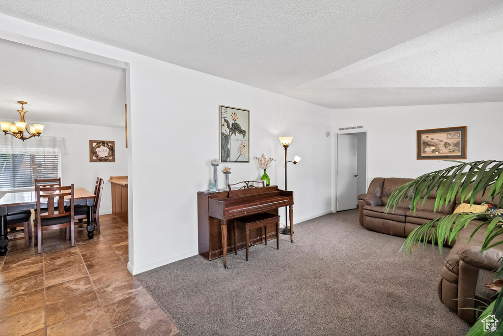 Carpeted living room featuring baseboards, an inviting chandelier, and a textured ceiling
