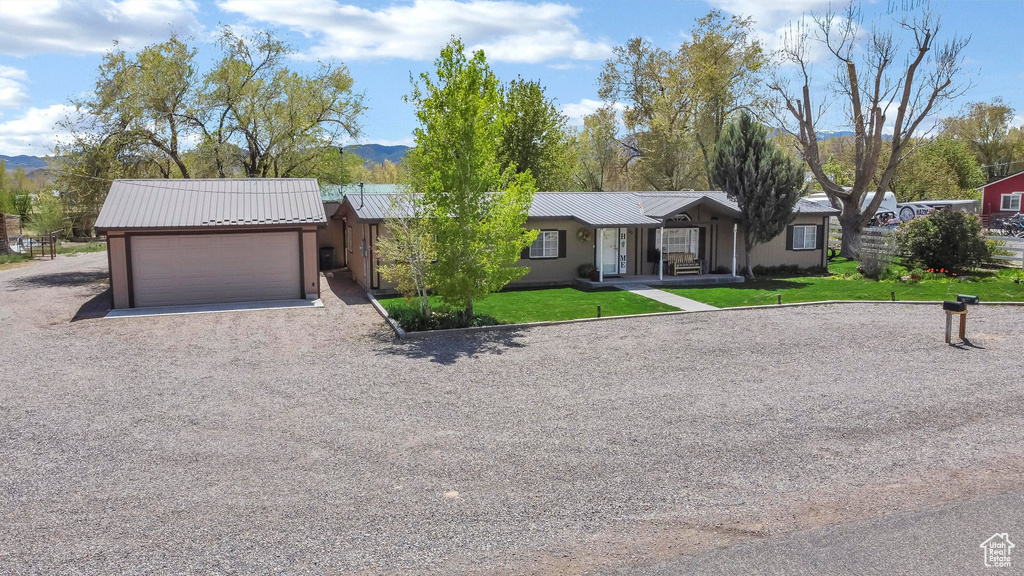 Single story home with an attached garage, a mountain view, metal roof, a front yard, and gravel driveway