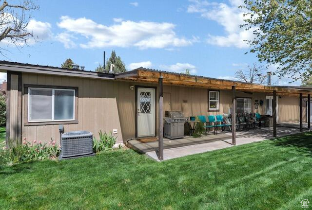 Rear view of house with a patio area, central AC, and a lawn