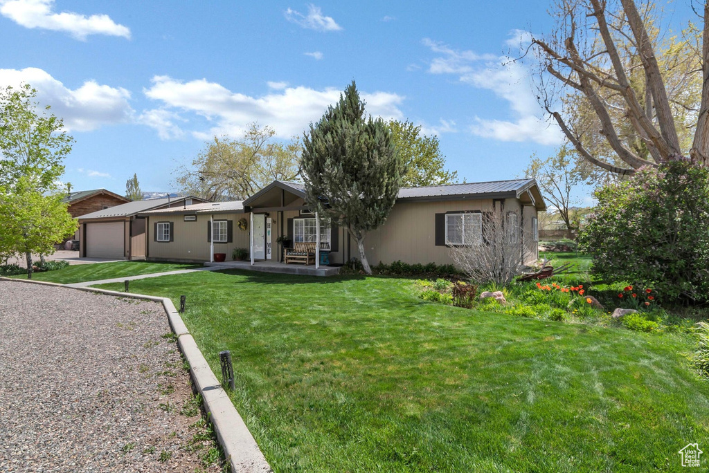 Back of property with a yard, metal roof, a porch, and an attached garage