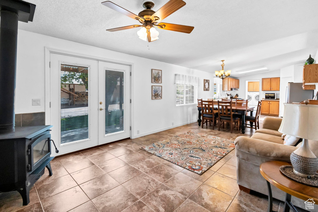 Tiled living room featuring a wood stove and ceiling fan with notable chandelier