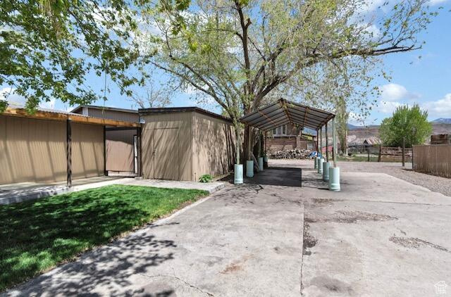 Exterior space featuring a detached carport, fence, and concrete driveway