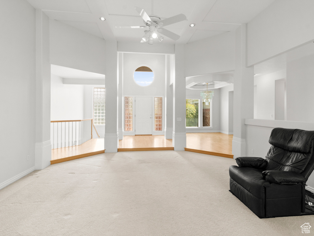 Living area with ceiling fan with notable chandelier, recessed lighting, carpet floors, a high ceiling, and baseboards