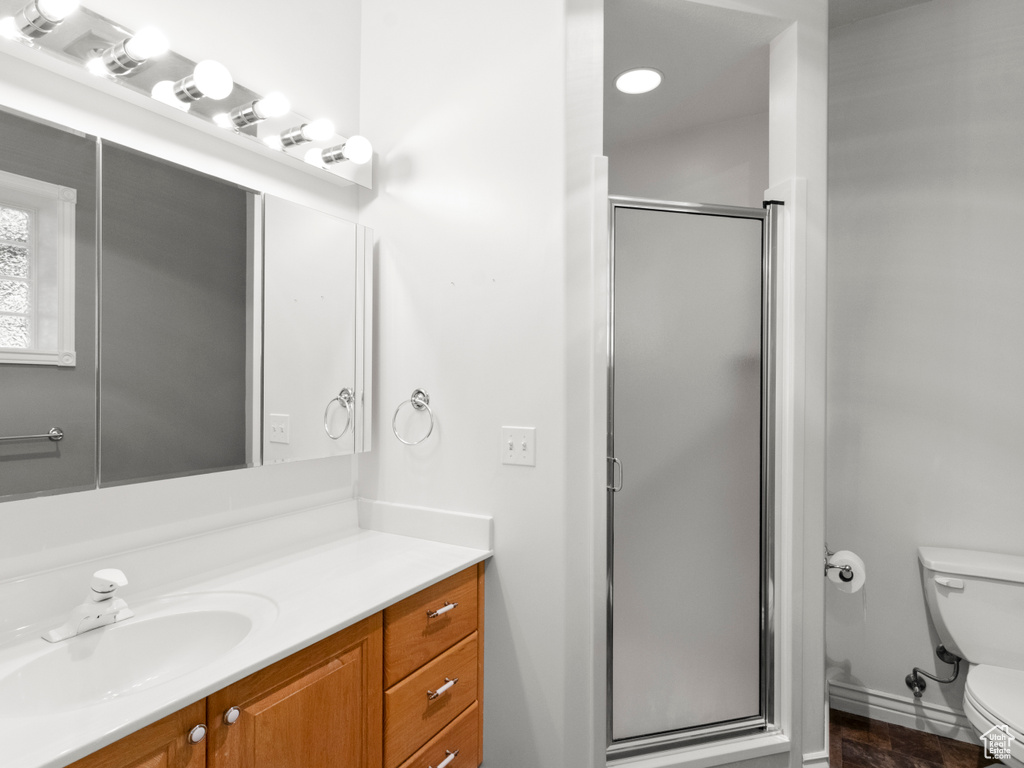 Bathroom featuring toilet, a shower stall, and vanity