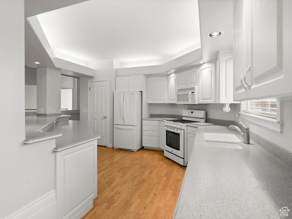 Kitchen with a sink, white cabinets, white appliances, light countertops, and recessed lighting